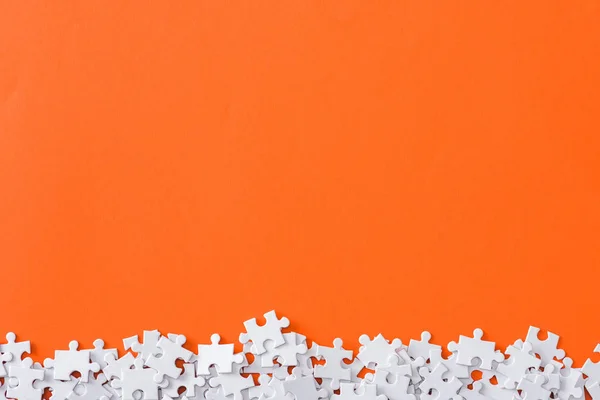 Vista superior de peças de quebra-cabeça incompletas isoladas em laranja com espaço de cópia — Fotografia de Stock
