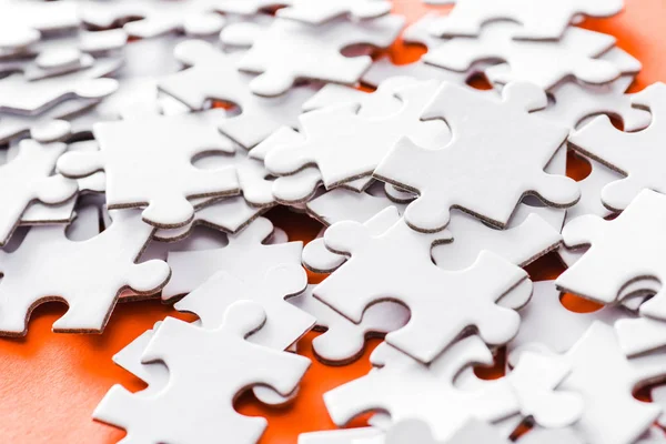 Selective focus of incomplete white jigsaw puzzle pieces on orange — Stock Photo