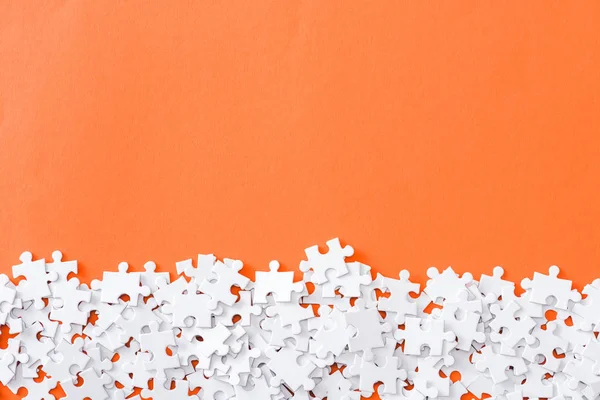 Vista superior de peças inacabadas de quebra-cabeça branco isolado em laranja com espaço de cópia — Fotografia de Stock