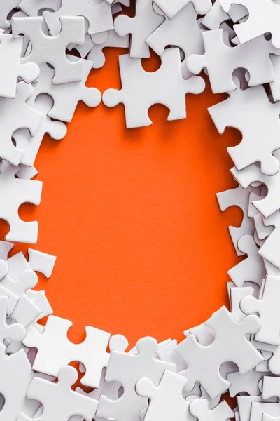 Top view of frame of white puzzle pieces on orange with copy space — Stock Photo