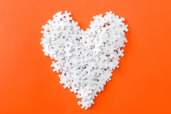 Top view of heart-shaped jigsaw puzzle pieces isolated on orange — Stock Photo