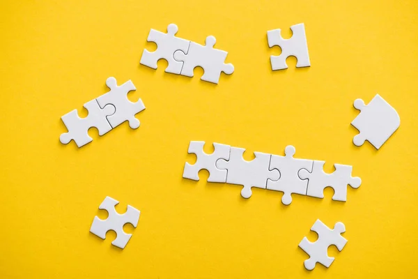 Top view of connected and unfinished puzzle pieces isolated on yellow — Stock Photo