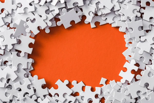 Vue du haut du cadre de puzzle blanc pièces sur orange — Photo de stock