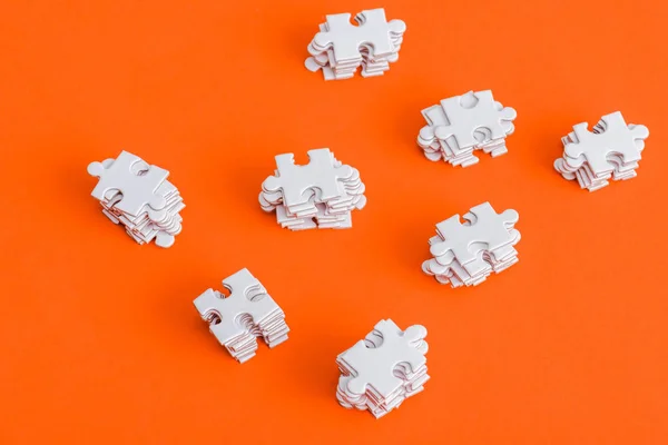 Top view of stacked white puzzle pieces on orange — Stock Photo