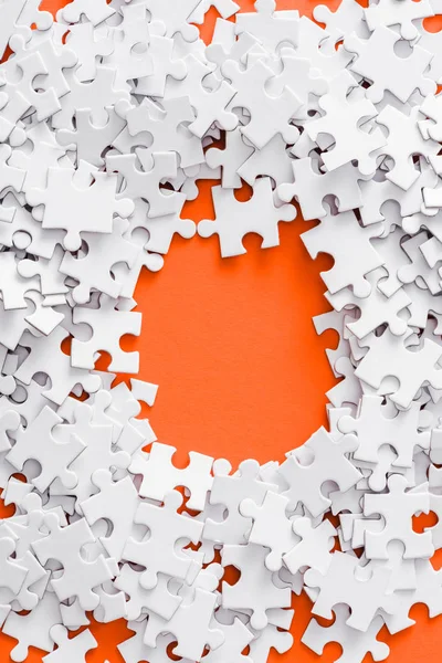 Top view of pile with white jigsaw puzzle pieces on orange — Stock Photo