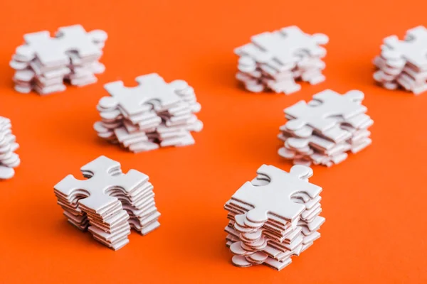 Top view of stacked white puzzle pieces on orange — Stock Photo