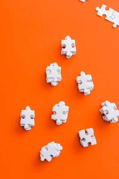 Top view of stacks with white puzzle pieces on orange — Stock Photo