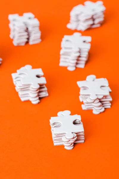 Enfoque selectivo de pilas con piezas de rompecabezas blanco en naranja - foto de stock
