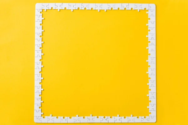 Vista superior do quadro com peças de quebra-cabeça branco conectado isolado no amarelo — Fotografia de Stock