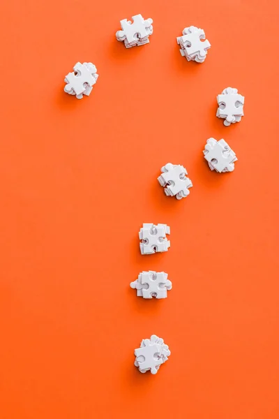 Вид зверху на форму позначки питання з білими шматочками головоломки на помаранчевому — стокове фото