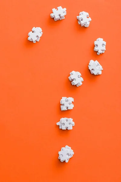 Vista superior de la forma signo de interrogación con piezas de rompecabezas blanco en naranja - foto de stock