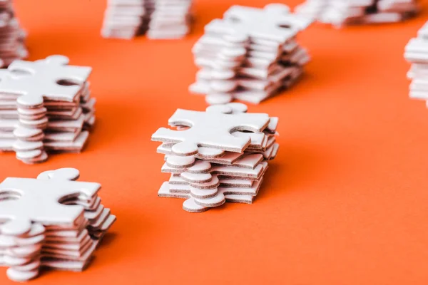 Enfoque selectivo de piezas de rompecabezas blanco pilas en naranja - foto de stock