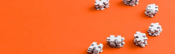 Tiro panorâmico de pilhas com peças de quebra-cabeça branco em laranja — Fotografia de Stock