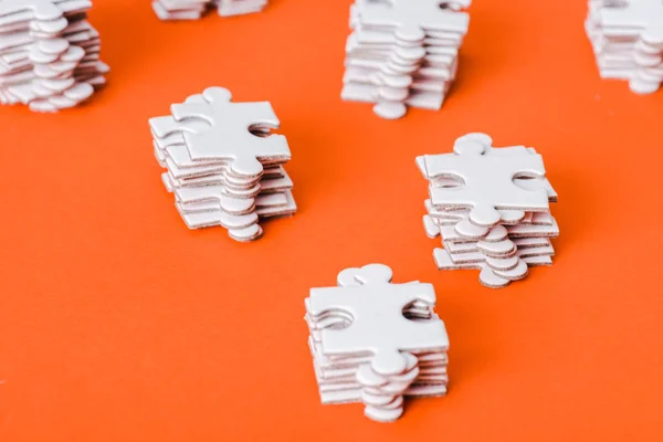 Selective focus of white jigsaw puzzle pieces stacks on orange — Stock Photo