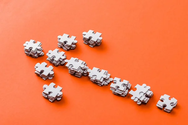 Vue du haut de la flèche de direction avec puzzle pièces sur orange — Photo de stock