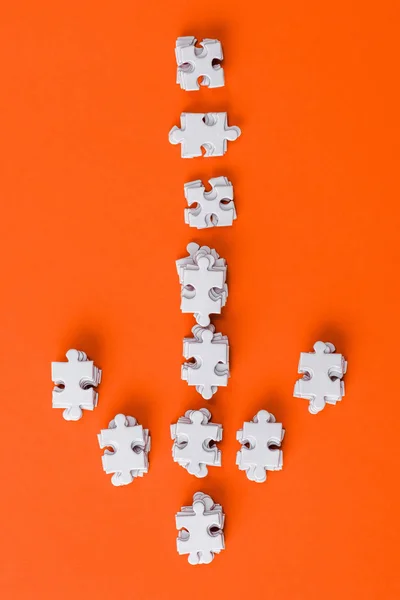 Vue du haut de la flèche de direction blanche avec des pièces de puzzle sur orange — Photo de stock