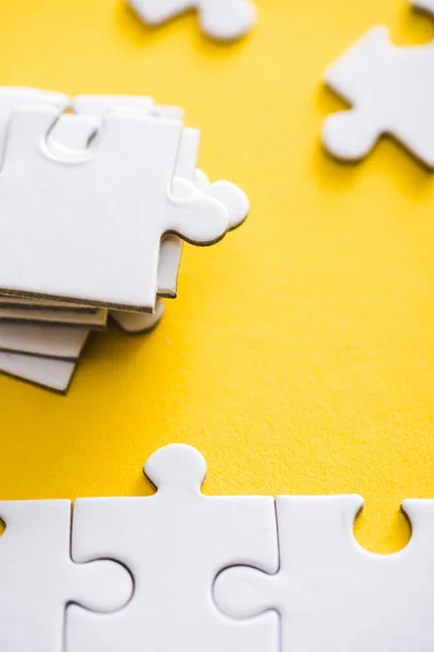 Selective focus of connected and incomplete puzzle pieces on yellow — Stock Photo