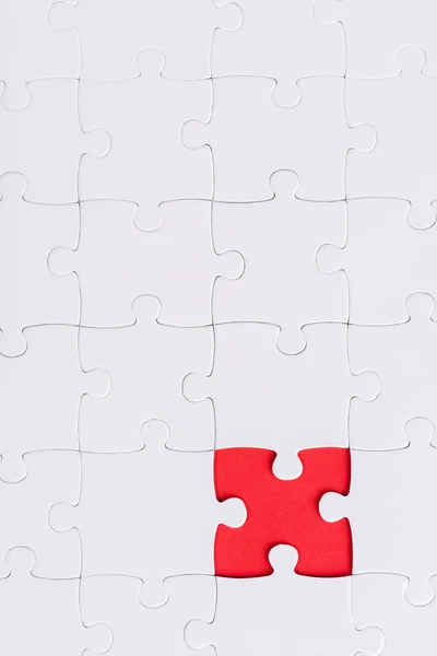 Top view of white connected puzzles with red shape — Stock Photo