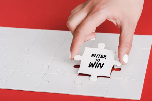 Cropped of woman holding jigsaw with enter to win lettering near connected white puzzle pieces on red — Stock Photo