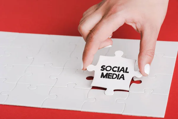Frau hält Puzzle mit Social-Media-Schriftzug in der Nähe verbundener weißer Puzzleteile auf Rot — Stockfoto