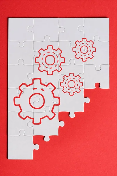 Top view of white connected puzzle pieces with gears settings isolated on red — Stock Photo