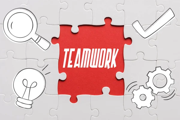 Top view of connected jigsaw puzzle pieces near teamwork letters — Stock Photo