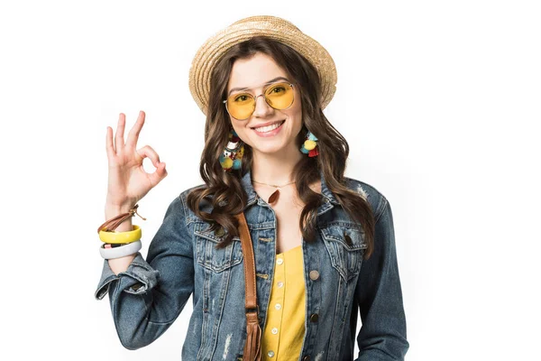 Smiling boho girl in boater and sunglasses showing okay sign isolated on white — Stock Photo