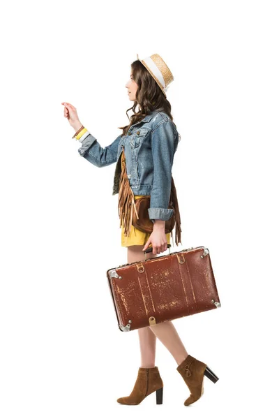 Vista lateral de chica boho en sombrero de paja sosteniendo maleta aislada en blanco - foto de stock