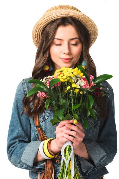 Feliz chica boho en sombrero de paja sosteniendo flores con los ojos cerrados aislados en blanco - foto de stock