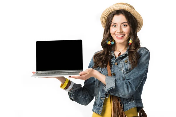 Cheerful boho girl in boater holding laptop with blank screen isolated on white — Stock Photo