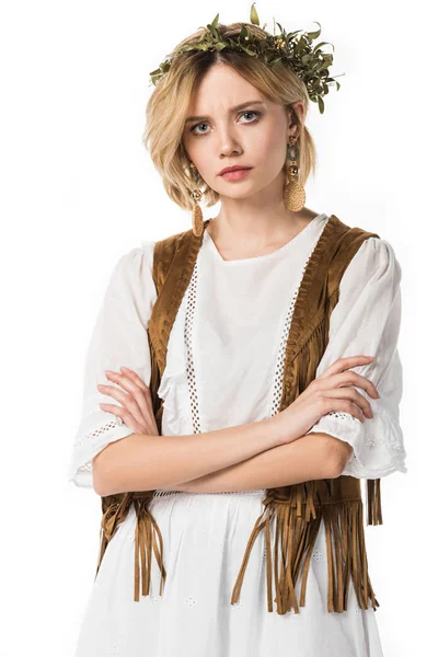 Сумна дівчина хіпі у вінку дивиться на камеру зі складеними руками ізольовані на білому — стокове фото