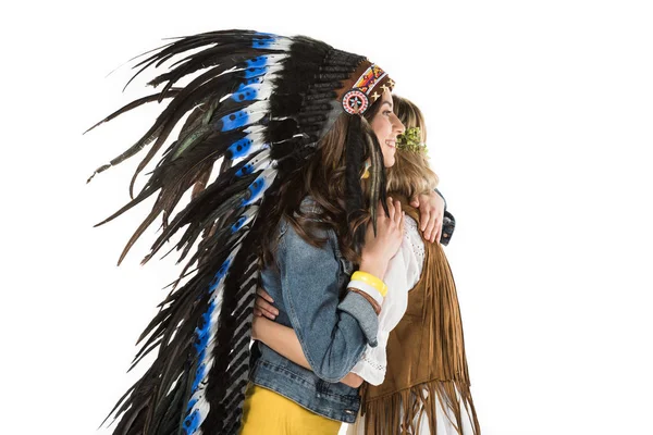 Two bisexual hippie girls in indian headdress and wreath embracing isolated on white — Stock Photo