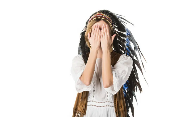 Giovane donna in copricapo indiano che copre il viso con le mani isolate su bianco — Foto stock
