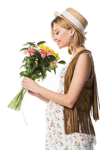 Vista laterale di donna hippie incinta sorridente che tiene i fiori isolati su bianco — Foto stock