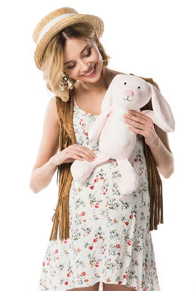 Smiling pregnant hippie woman holding toy rabbit isolated on white — Stock Photo