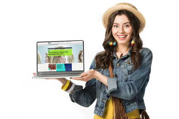 KYIV, UCRAINA - 4 FEBBRAIO 2019: ragazza hippie sorridente in cappello di paglia che tiene il laptop con il sito web bbc sullo schermo isolato su bianco — Foto stock
