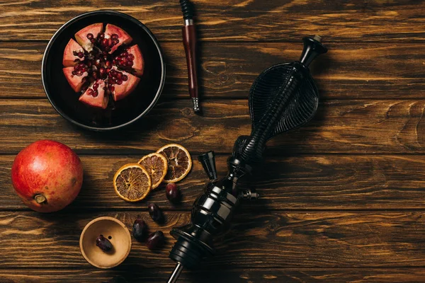 Vue de dessus du narguilé, grenats, raisins et oranges coupées séchées sur la surface en bois — Photo de stock