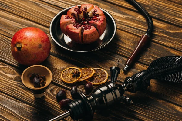 Narguilé, grenats, raisins et oranges coupées séchées sur la surface en bois — Stock Photo