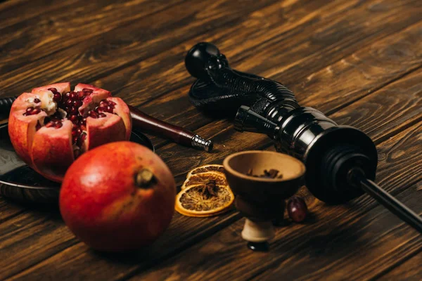 Hookah, garnets, grape and dried cut oranges on wooden surface — Stock Photo