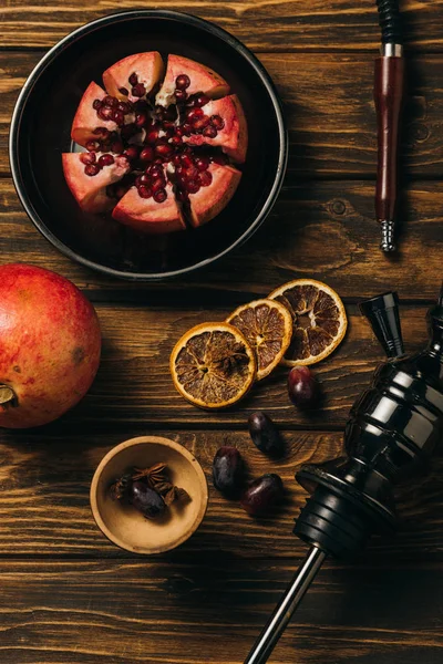 Vue de dessus des grenats, raisins, oranges coupées séchées et narguilé sur la surface en bois — Photo de stock