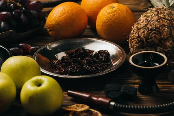 Кальян, тютюн, апельсини, яблука, ананас, виноград і вугілля на дерев'яній поверхні — стокове фото