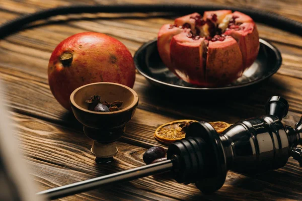 Garnets, dried oranges and hookah on wooden surface — Stock Photo