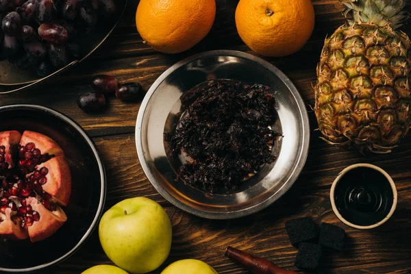 Blick von oben auf Granat, Trauben, getrocknete geschnittene Orangen, Äpfel, Ananas, Tabak und Wasserpfeife auf Holzoberfläche — Stockfoto