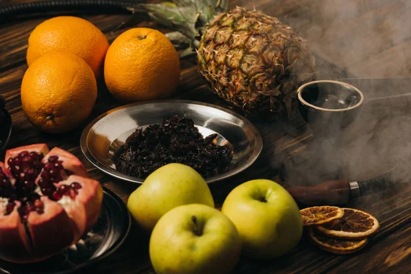 Hookah, tabaco, manzanas, naranjas, granate y piña en superficie de madera - foto de stock