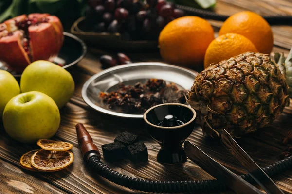 Enfoque selectivo de frutas exóticas, tabaco y narguile en la superficie de madera - foto de stock