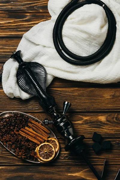 Top view of cinnamon, dried oranges and hookah on wooden surface — Stock Photo