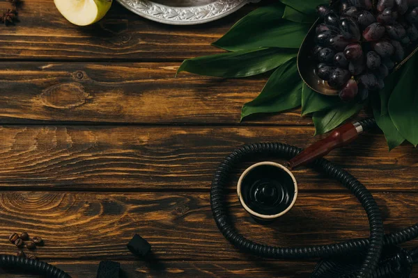 Top view of hookah, grapes, coffee grains and green leaves on wooden surface — Stock Photo