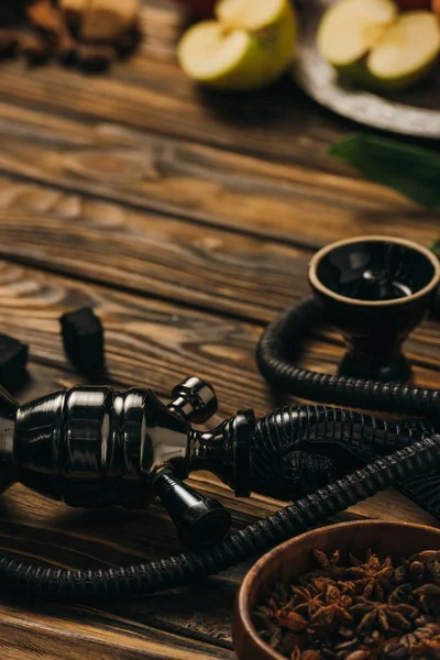 Selective focus of apples, hookah, cinnamon and coals on wooden surface — Stock Photo