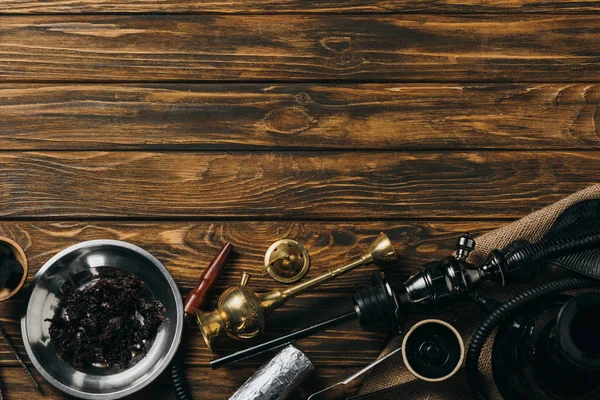 Vue de dessus du narguilé, du tabac et des charbons sur la surface en bois — Photo de stock