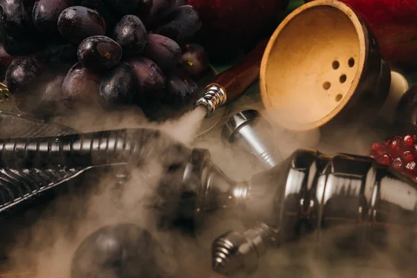 Enfoque selectivo de uvas frescas sabrosas, granate y narguile en el humo - foto de stock